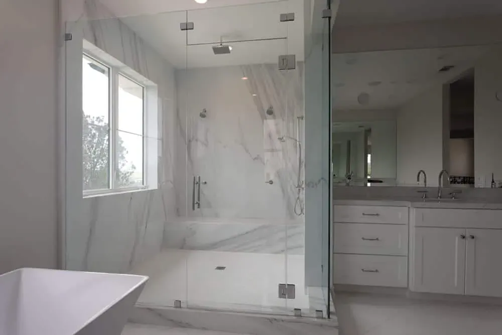Marble shower and vanity with a window and freestanding tub
