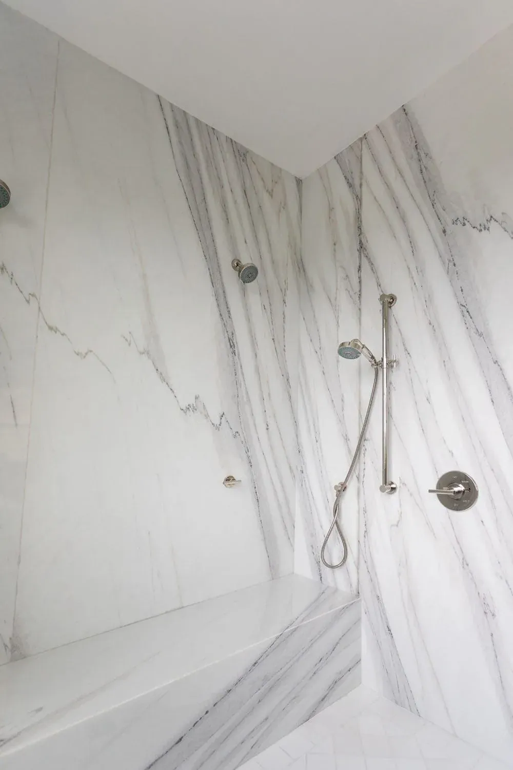 Marble slab shower with a rain head and handheld shower