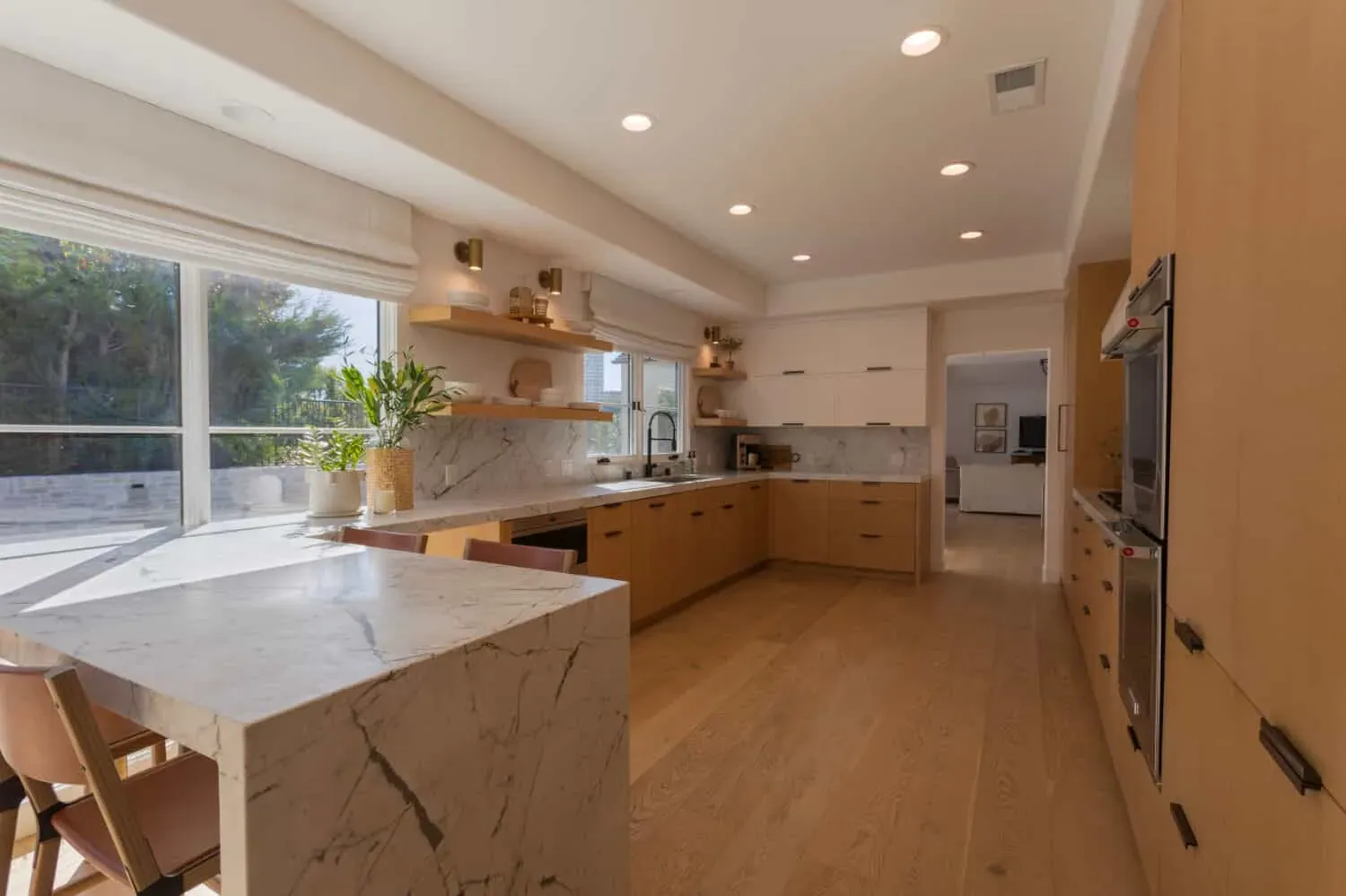 Marble waterfall island against oak cabinetry and wood flooring