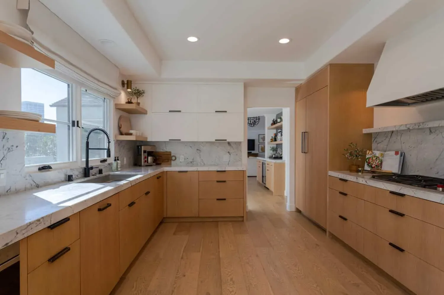 Modern kitchen in light wood and white with flat-panel doors and a window over the sink