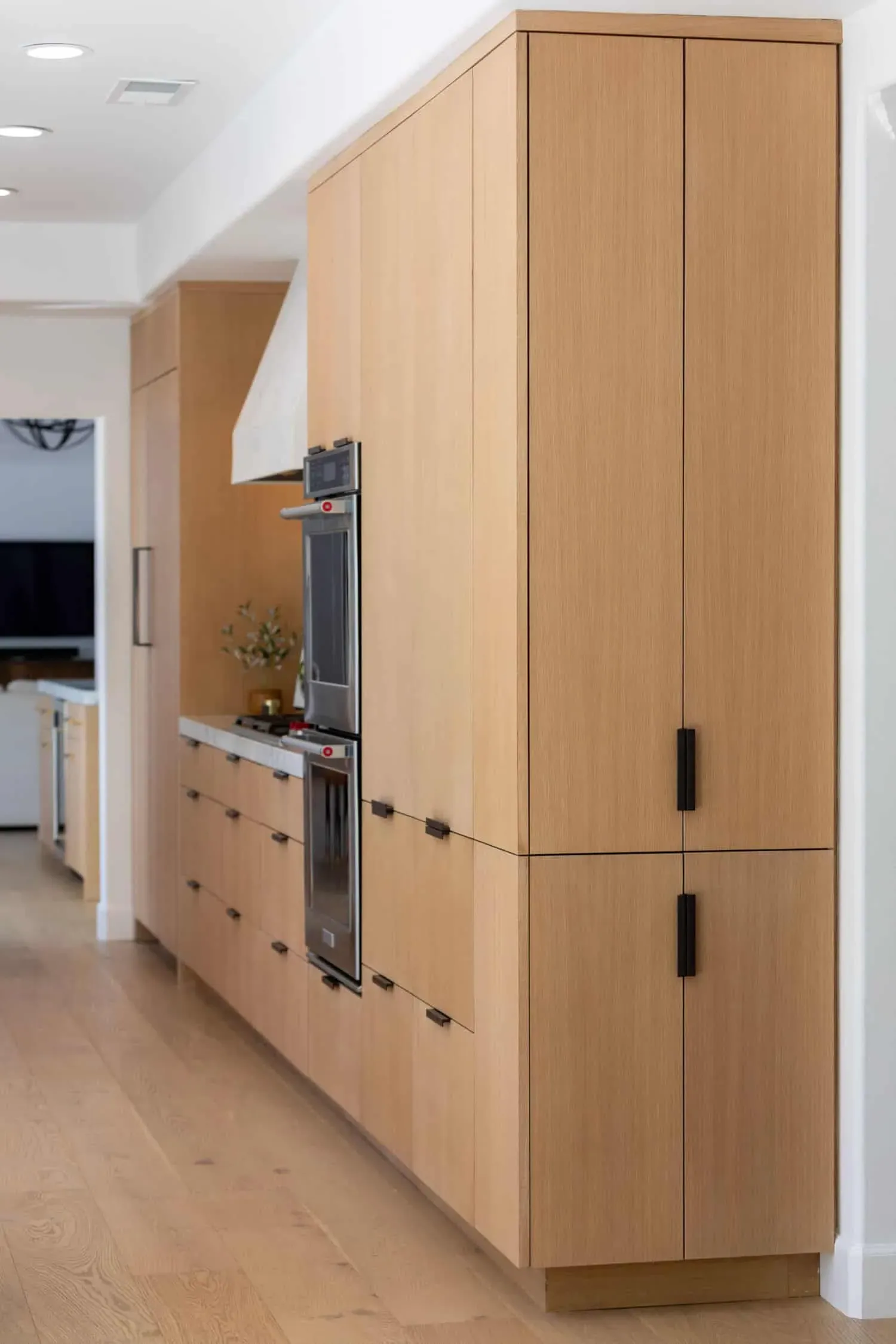 Oak cabinetry with an integrated refrigerator and wall ovens