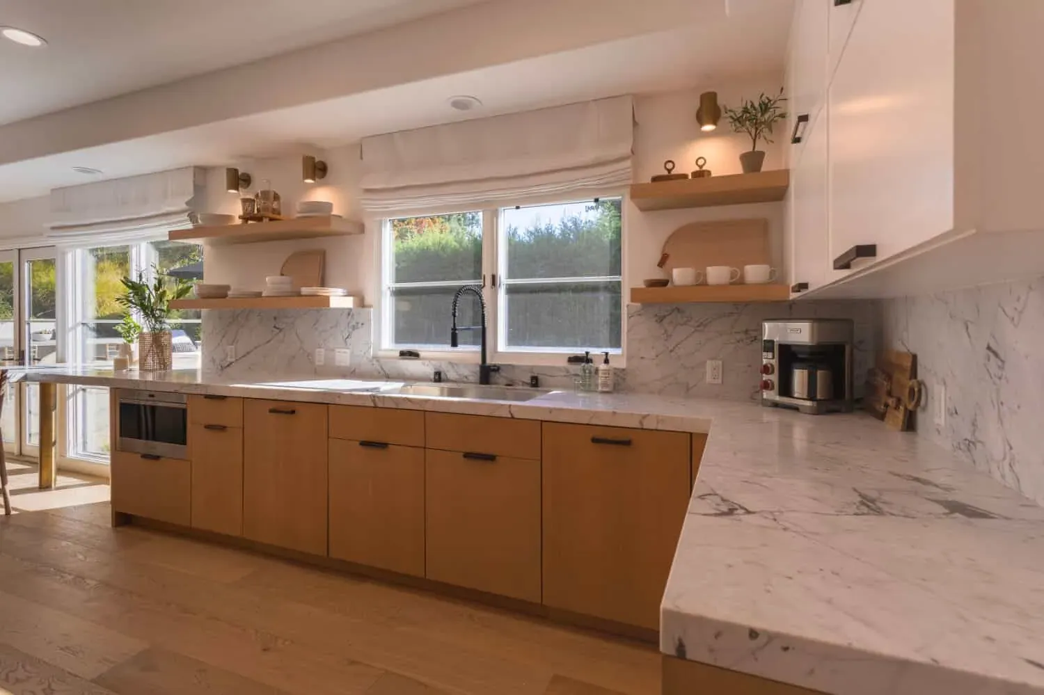 Oak cabinetry with a marble backsplash, sink and window