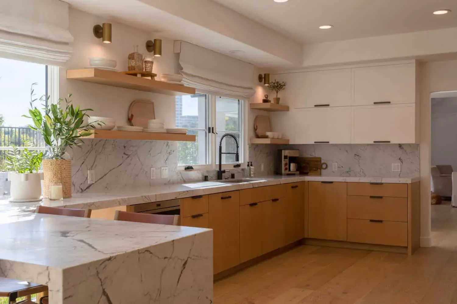 Oak cabinetry with open shelving, marble counters and a black tap