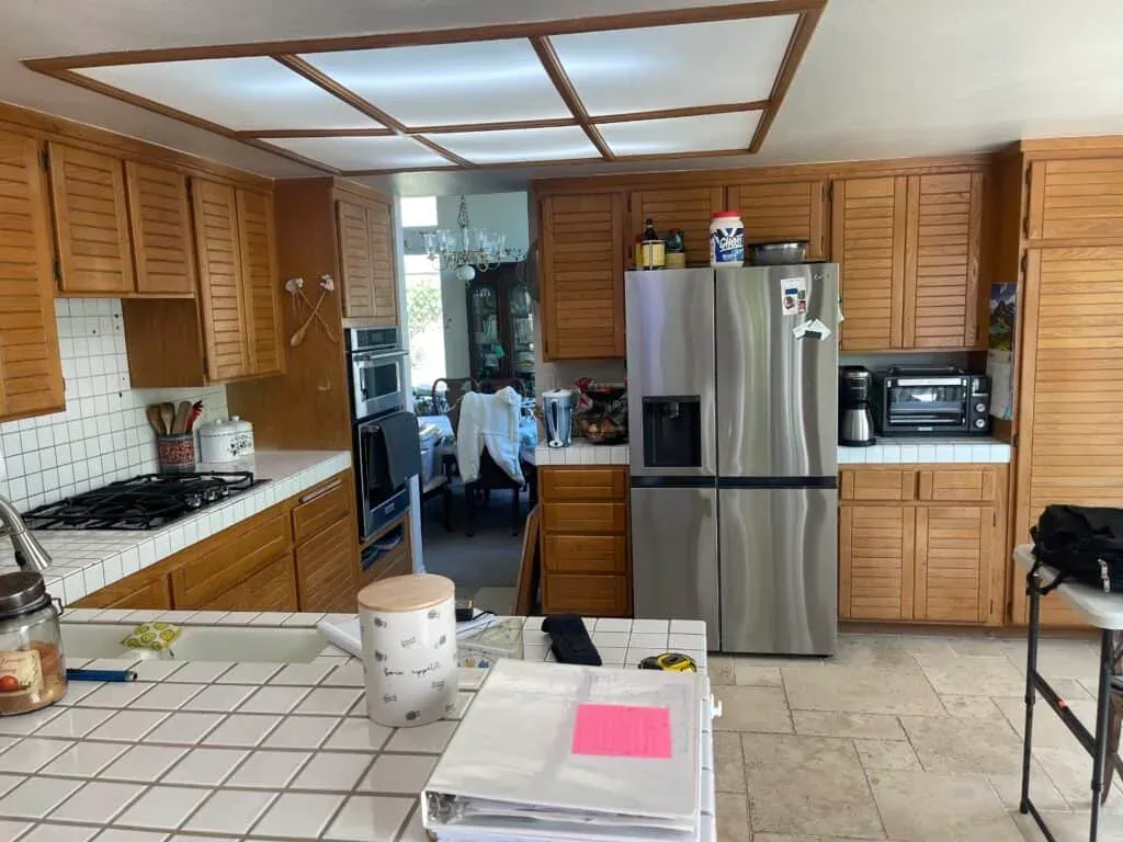 Oak kitchen before remodeling, showing the original ceiling light box and stainless fridge