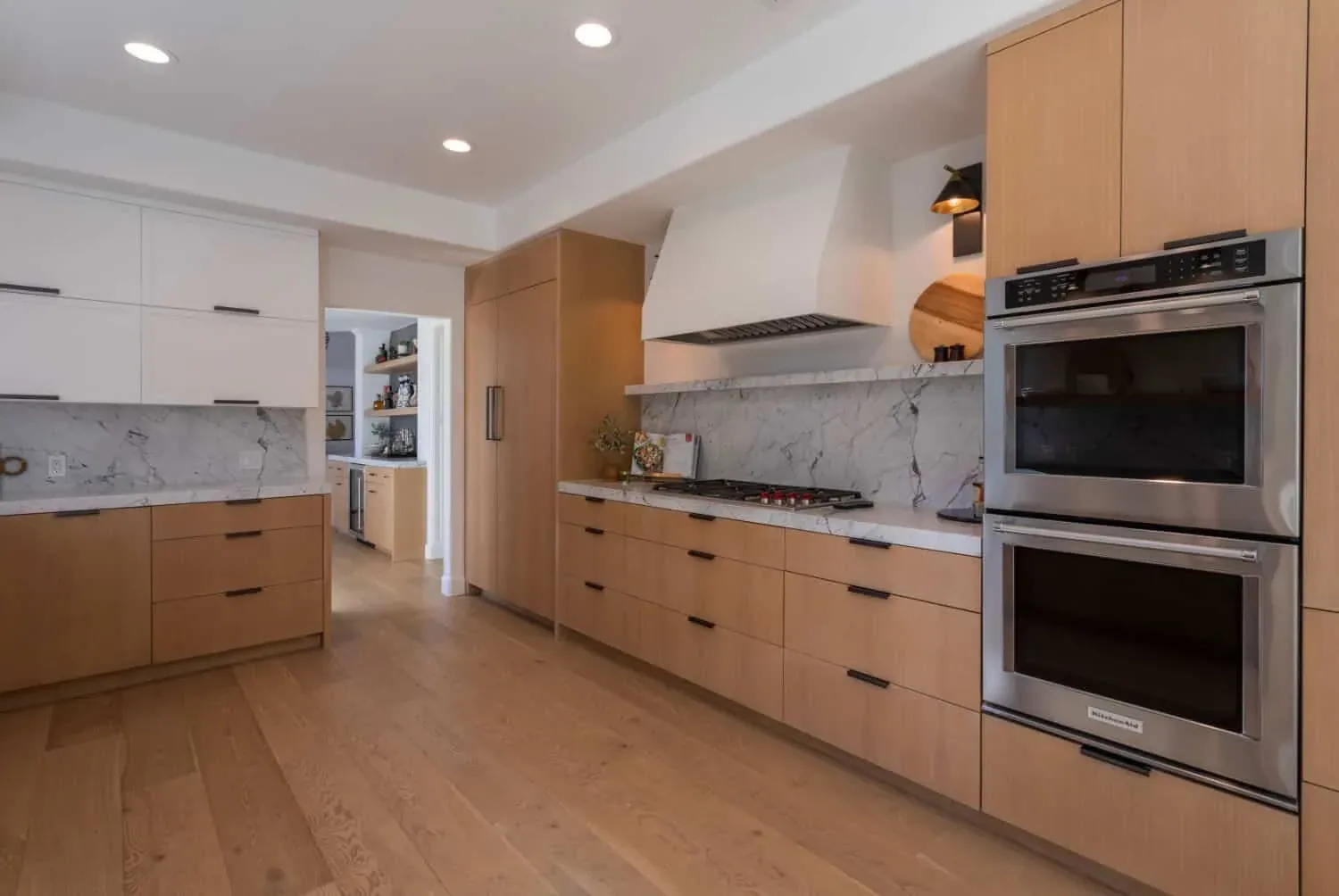 Oak kitchen run with a plaster hood, marble backsplash and wall ovens