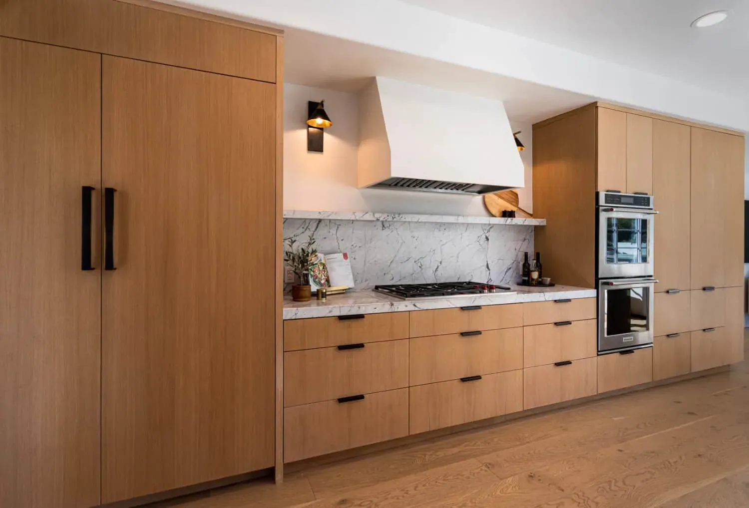 Oak kitchen with a white plaster hood, cooktop and double wall ovens