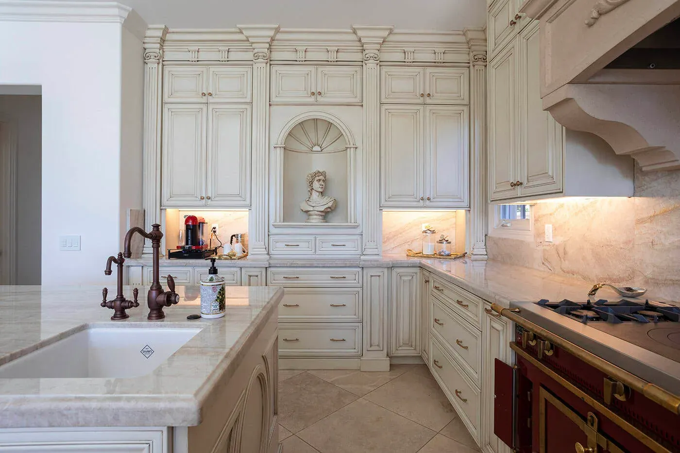 Ornate cream kitchen with an arched niche above the range and a farmhouse sink
