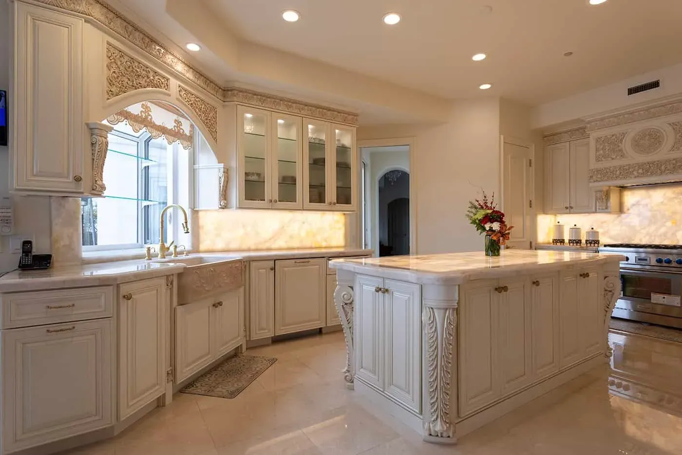 Ornate cream kitchen with a carved island and glass-front cabinets