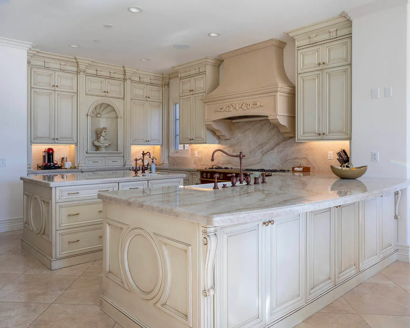 Ornate cream kitchen with a carved range hood and a large marble island