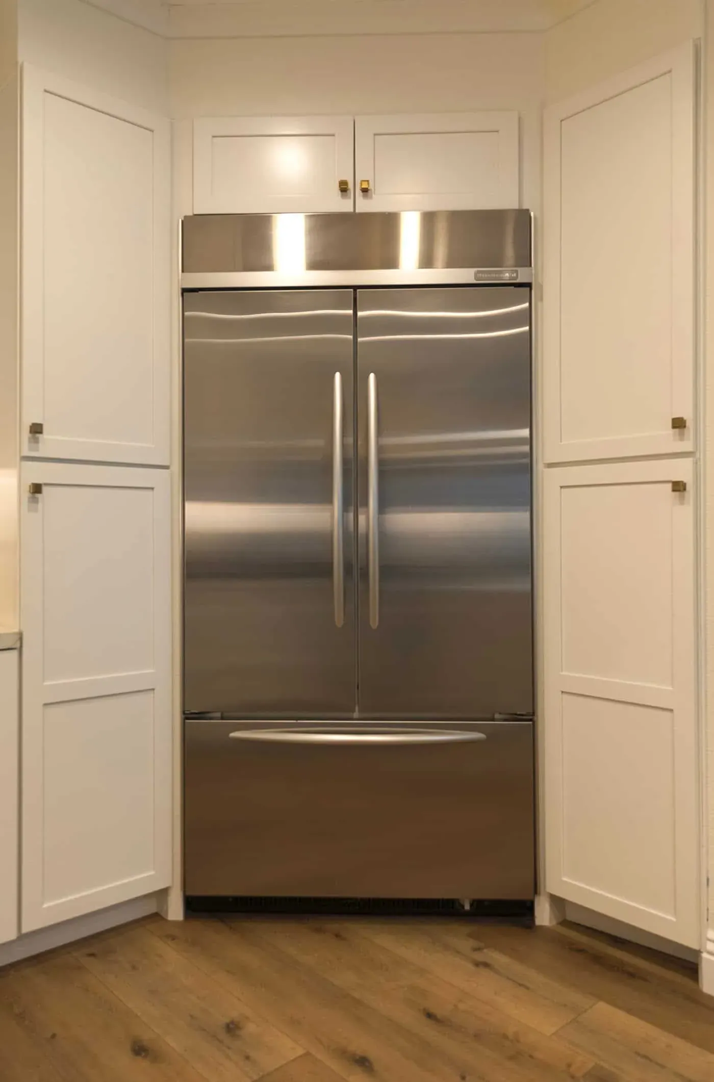 Panelled cabinetry flanking a tall stainless refrigerator