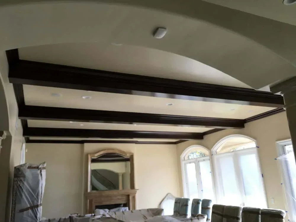 Room with dark exposed ceiling beams and arched windows