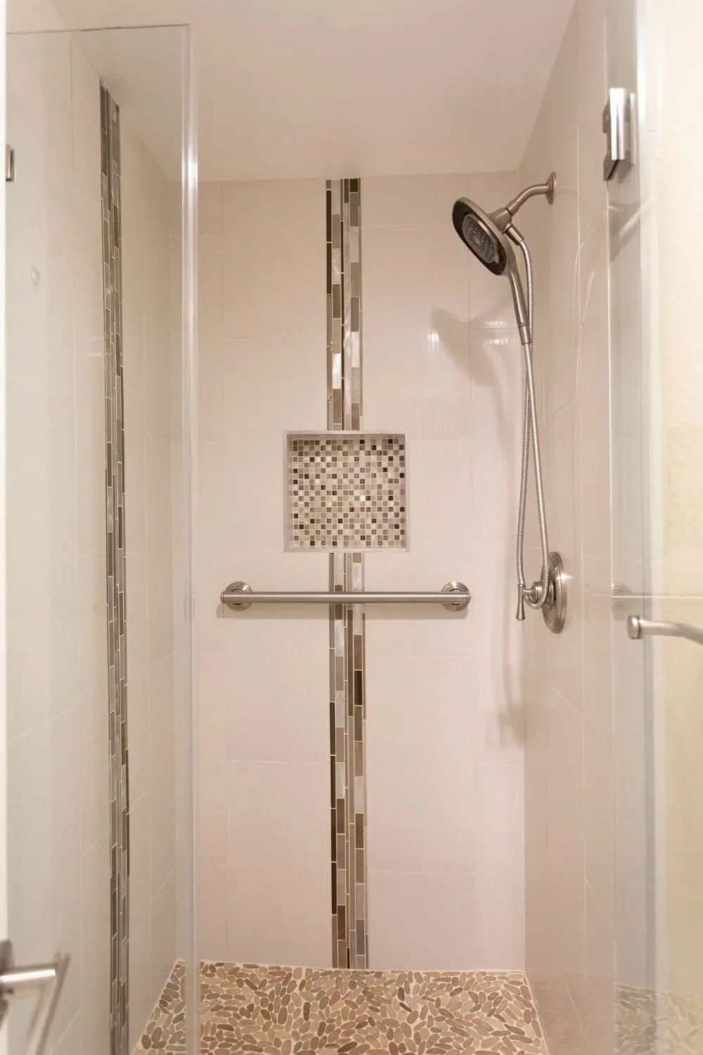 Shower with a mosaic accent strip, recessed niche and grab bar