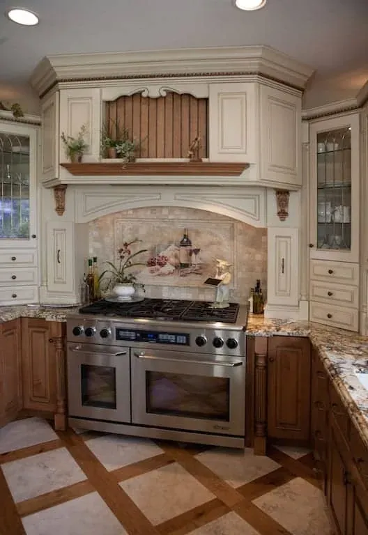 Stainless range beneath a carved hood with a decorative tile mural