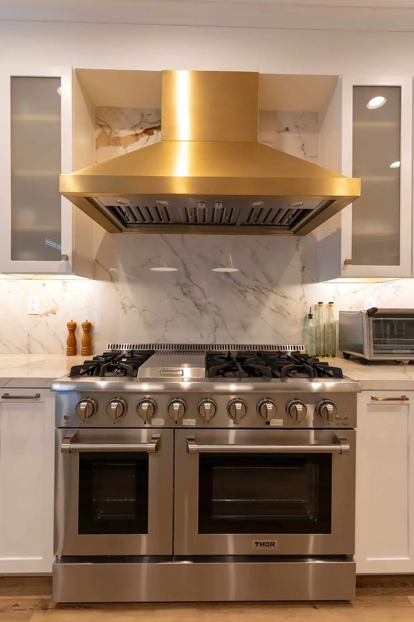Stainless range with a brass hood and a marble slab backsplash