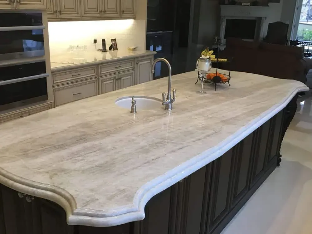 Thick cream stone island countertop with an ogee edge, an undermount sink and a gooseneck tap