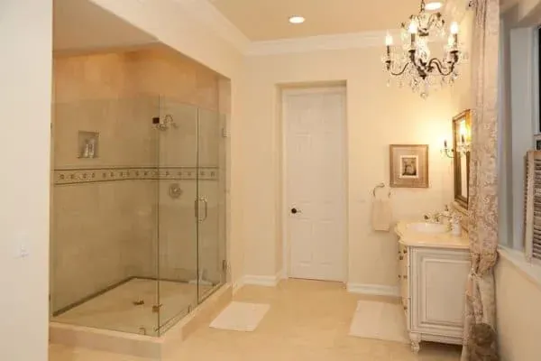 Tiled walk-in shower with a glass enclosure beneath a chandelier