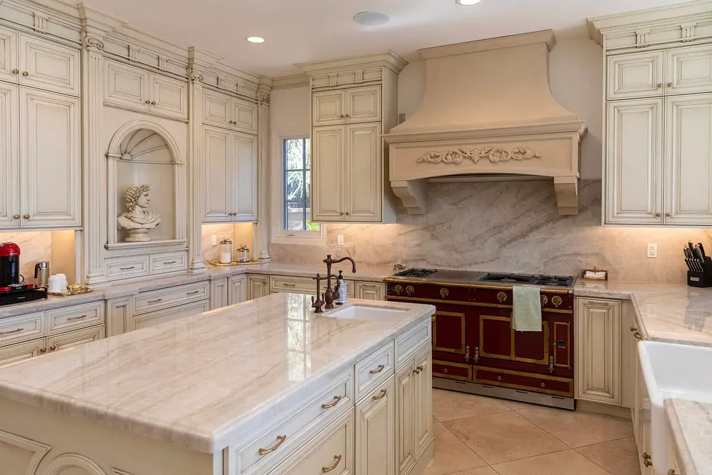 Traditional kitchen with an arched niche, red range and stone island