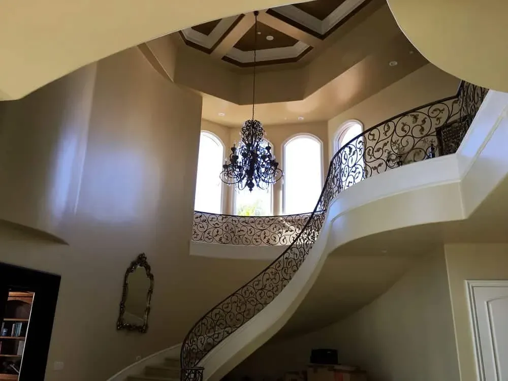 Two-storey entry hall with a curved wrought-iron staircase, chandelier and domed ceiling