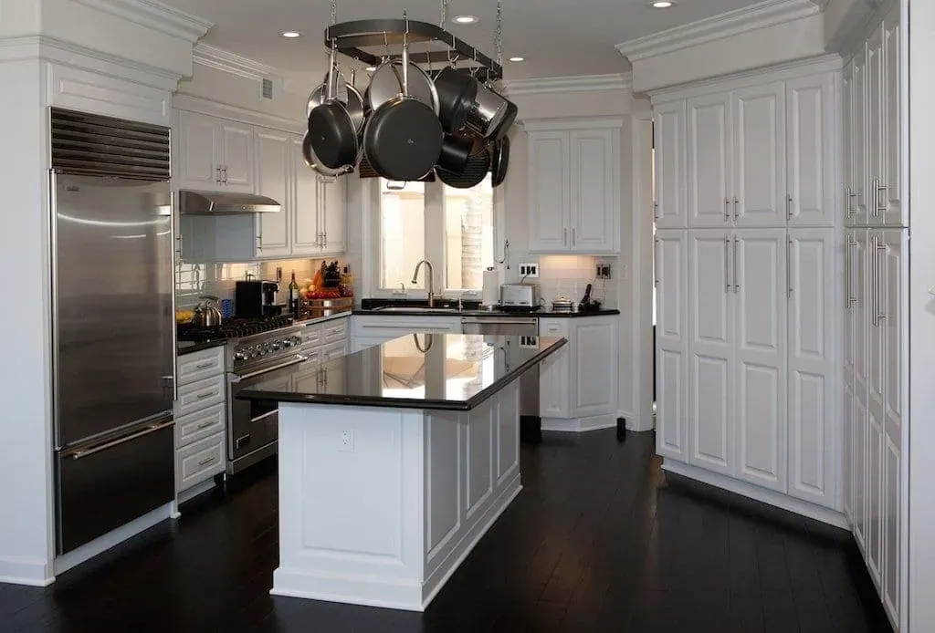 White kitchen with a pot rack, stainless range and dark island