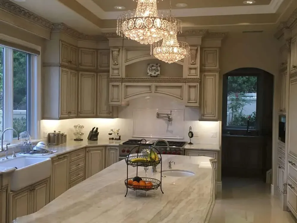 Wide kitchen view with a chandelier, island, range hood and an arched doorway