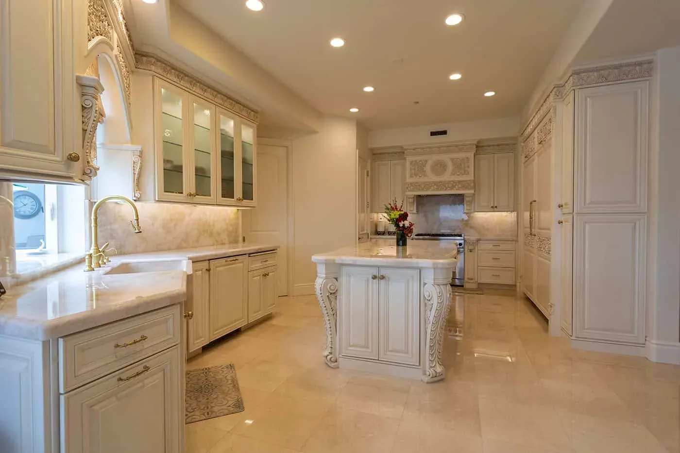 Wide view of a carved cream kitchen with island and glass cabinets