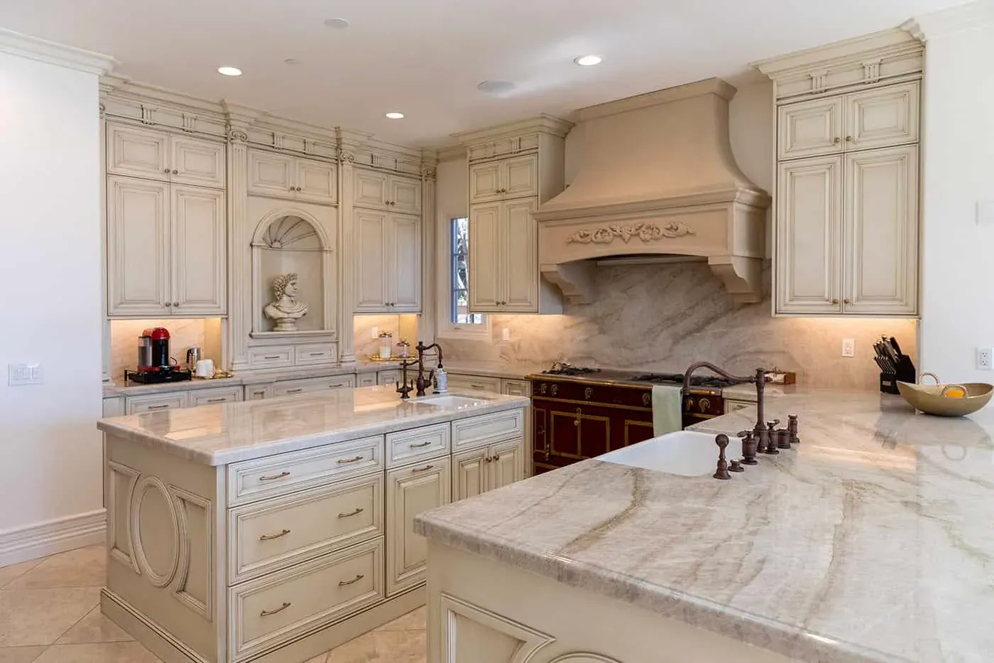 Wide view of a cream traditional kitchen with island and carved hood