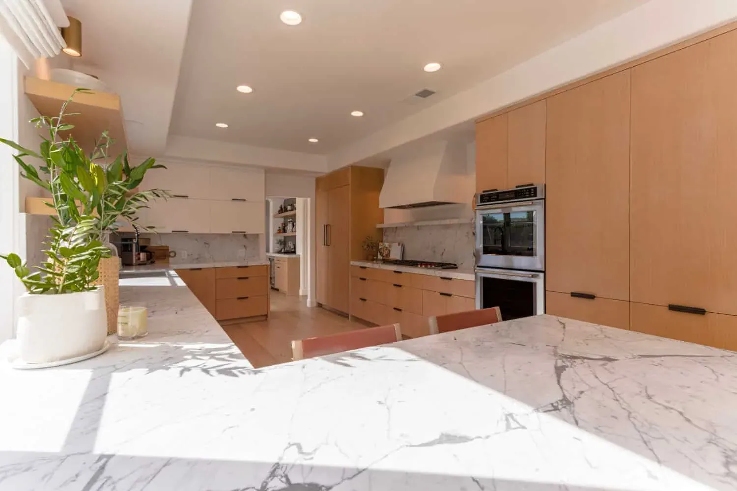 Wide view of an oak kitchen with a marble island and wall ovens